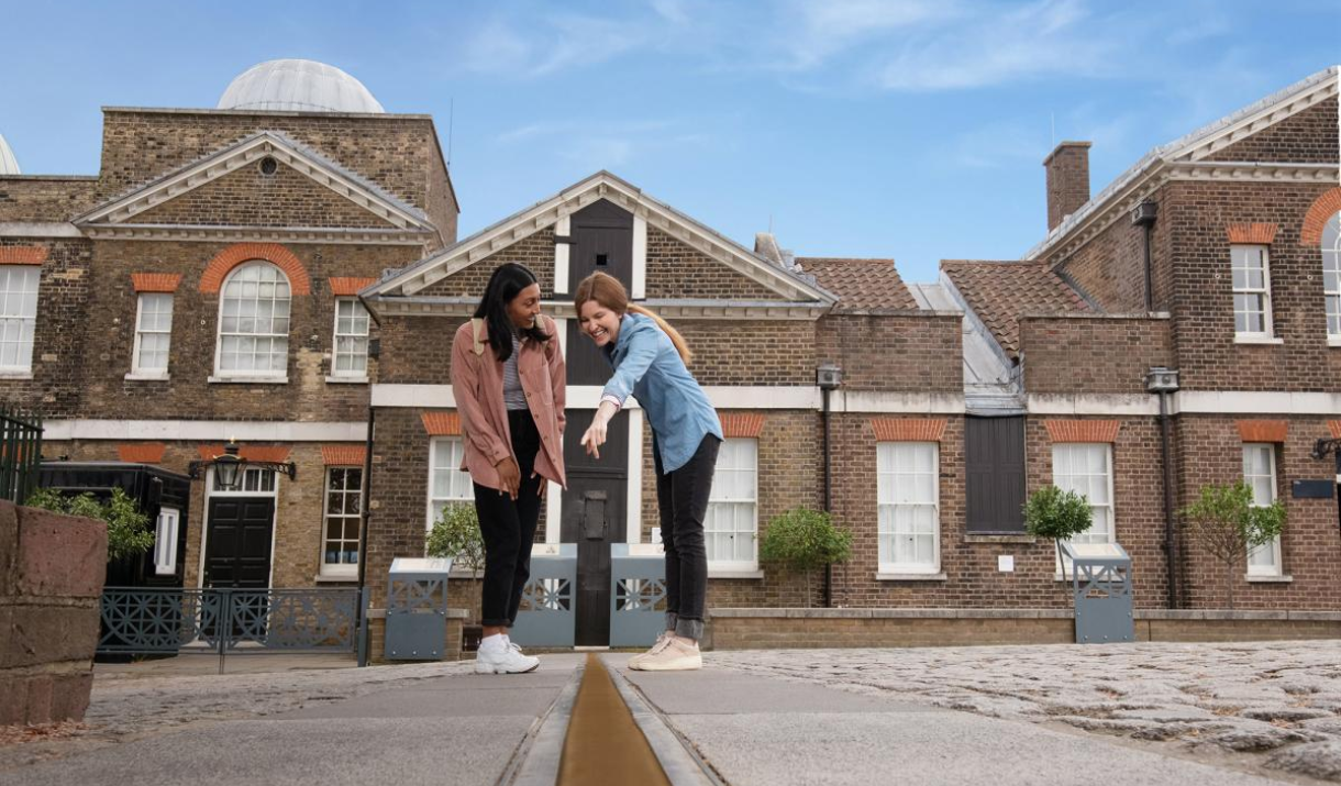Two women point at the Meridian Line